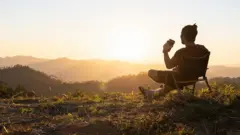 شخص يجلس على ربوة تكسوها الخضرة