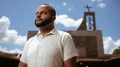 Junior Henrique da Silva com uma igreja ao fundo