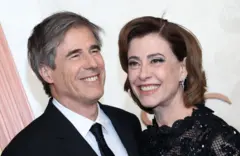 Walter Salles e Fernanda Torres sorrindo em frente a painel de evento