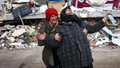 Unas mujeres reaccionan en el lugar donde se derrumbó un edificio tras un fuerte terremoto en el distrito de Elbistan de Kahramanmaras (Turquía).
