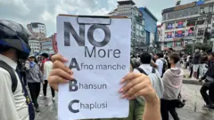 नयाँ बानेश्वरमा भदौ २३ गतेको प्रदर्शनमा प्रदर्शित प्लाकार्डमा लेखिएको आफ्नो मान्छे, भनसुन र चाप्लुसीको विरोधका शब्दहरू