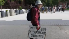 Пожилой человек с плакатом We <3 our international students.