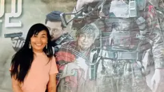 লিলি নাইং চিয়, সামরিক বাহিনীর একটি প্রোপাগাণ্ডামূলক ছায়াছবির পোস্টারের সামনে 