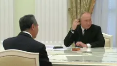 President Putin sits opposite Wang Yi