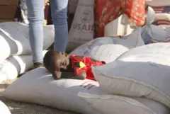 Un enfant couché sur un sac de céréales avec le logo de l'USAID