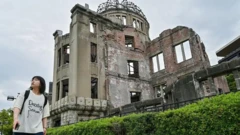 زنی در حال عبور از کنار یک ساختمان ویران