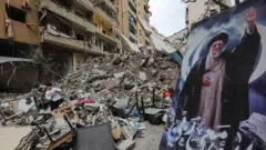 Um menino está em meio aos escombros de um prédio destruído, ao lado de um retrato do falecido líder supremo do Irã, o aiatolá Ali Khamenei, durante uma visita guiada organizada pelo grupo militante Hezbollah, apoiado pelo Irã, na área de Haret Hreik, nos subúrbios do sul de Beirute, em 20 de abril de 2026.