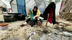 Uma Shadi washing clothes near the tents 