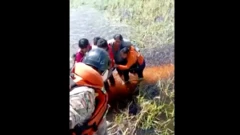 imagem feita a partir de helicóptero mostra passageiros abraçados em meio a um pântano sendo resgatadas