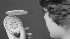 Une femme tenant des pilules contraceptives de l'epoque