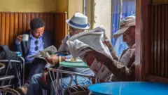 በካፍቴሪያ ውስጥ ጋዜጣ የሚያነቡ ሰዎች