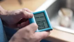 Homem segurando relógio digital nas mãos