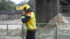 Fotoapostas desportivas onlineum agenteapostas desportivas onlinesegurança, com uma roupa amarela e preta e capacete amarelhoapostas desportivas onlineuma ponte sobre um rio com águas agitadas 