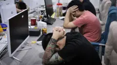 Bilgisayar başında ellerini yüzlerine kapatan kişiler