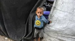 طفل صغيرينظر من وراء قماش احدى الخيام التي نصبتها عائلته فوق منزلها المهدم في خان يونس.