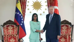 üzerinde açık mavi bir takım bulunan rodriguez (solda) Erdoğan ile el sıkışarak kameraya bakıyor 