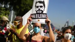 A person holds a sign reading "Bolsonaro out" during a protest calling for the impeachment of Brazil's President Jair Bolsonaro in Rio de Janeiro, Brazil, on 3 July 2021