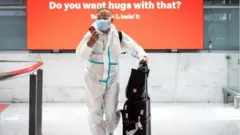 ผู้โดยสารเครื่องบินสวมชุดป้องกันการติดเชื้อ