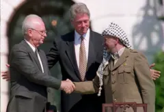 Aperto de mão entre o líder da OLP, Yasser Arafat (direita) e primeiro-ministro israelense, Yitzahk Rabin