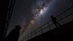 شخصان يراقبان نجوماً في جو صافٍ ومظلم