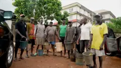 Awọn baba arugbo mẹsan to n fọ mọto, ikọọkan wọn gbe ike ipọnmi lọwọ, wọn wọ oniruuru asọ ati sokoto penpe, ti wn si de fila bẹntigọọ sori.