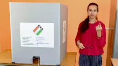 कर्नाटक निवडणुकीत मत दिल्यावर पोलिंग बूथशेजारी उभी राहून बोटावरची शाई दाखवणारी मतदार
