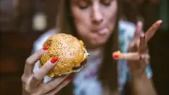 Mujer comiendo una hamburguesa
