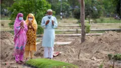 করোনায় আক্রান্ত হয়ে মৃত্যুবরণ করা একজনের কবরে সামনে মোনাজাত করছেন কয়েকজন স্বজন।
