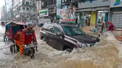 बाङ्ग्लादेशको राजधानी ढाकामा पानी जमेको सडकमा यात्रा गरिरहेकाहरू।