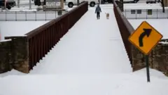 Anna Thomasson walks her dog, Penny, across the White Rock Lake Spillway after winter weather caused electricity blackouts in Dallas, Texas, U.S. February 18, 2021