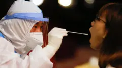 北京人民大會堂內一名女記者（右）進場採訪全國人大會議閉幕前接受咽拭子新冠病毒檢測（11/3/2001）