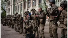 Soldados ucranianos descargan sus armas al llegar a un centro para recibir atenci{on médica.