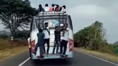 தொங்கியபடி செல்லும் மாணவர்கள்.