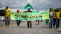 Manifestantes seguram cartazes pedindo fechamento do STF e do Congresso durante ato pró-Bolsonaro
