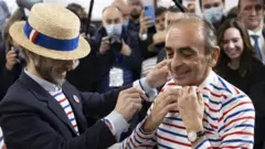 المجادل الفرنسي اليميني المتطرف إريك زمور يحاول ارتداء قميص مقلم أثناء زيارته لمعرض "صنع في فرنسا" في قاعة المعارض بورت دو فرساي في باريس ، فرنسا ، 14 نوفمبر 2021