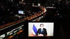 ภาพพล.อ. ประยุทธ์ จันทร์โอชา บนหน้าจอโทรศัพท์วางหน้ารถ ฉากหลังเป็นถนนในกรุงเทพฯ