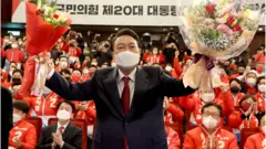 윤석열 대통령 당선인이 10일 새벽 서울 여의도 국회도서관에 마련된 '국민의힘 제 20대 대통령선거 개표상황실'을 찾아 꽃다발을 받고 있다
