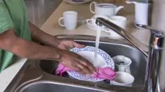 Une femme de ménage faisant la vaisselle