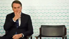 Bolsonaro sentadoganhar dinheiro na roleta onlinecadeira durante evento olhando para baixo