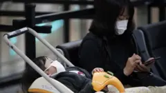 Mulher e criança com máscaras no aeroporto internacional de Tóquio