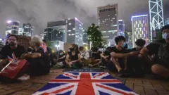 A British Union Jack flag is displayed as protesters gather along a fenced-off Victoria Harbour pier in Hong Kong