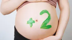 Close em uma barriga de grávida pintada com o número 2