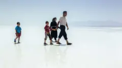 Uma família caminha pela crosta de sal seca do Lago Úrmia, no Irã