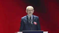 Kemal Kılıçdaroğlu genel başkanlığı kaybettiği 38. Kurultay'da konuşma yapıyor. Arkasında kırmızı bir fon var. Ayakta duruyor.