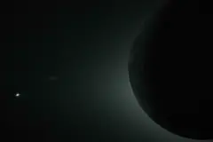 Contorno oscuro de la Luna con el resplandor del Sol por detrás y Venus como un punto brillante en la esquina inferior izquierda.