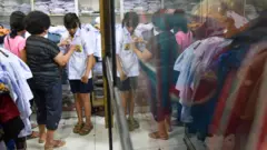 Seorang siswa mencoba seragam sekolah yang dijual di Pasar Pringgan, Medan, Sumatera Utara, Jumat (14/7)