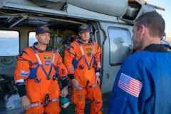 O comandante Reid Wiseman (à esquerda) e o astronauta Jeremy Hansen são recebidos pelo administrador da NASA, Jared Isaacman, a bordo do John P. Murtha.