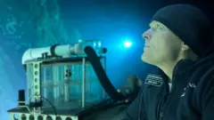 David Lochridge in a submersible looking out at an underwater reef 