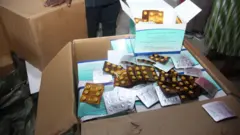 Aworan ayederu oogun naa ninu awọn paali ti wọn ko o si, awọn oṣiṣẹ NAFDAC kan wa ninu yara naa ti wọn duro ti i