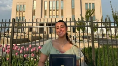 Caroline sorrindo em frente a um edifício